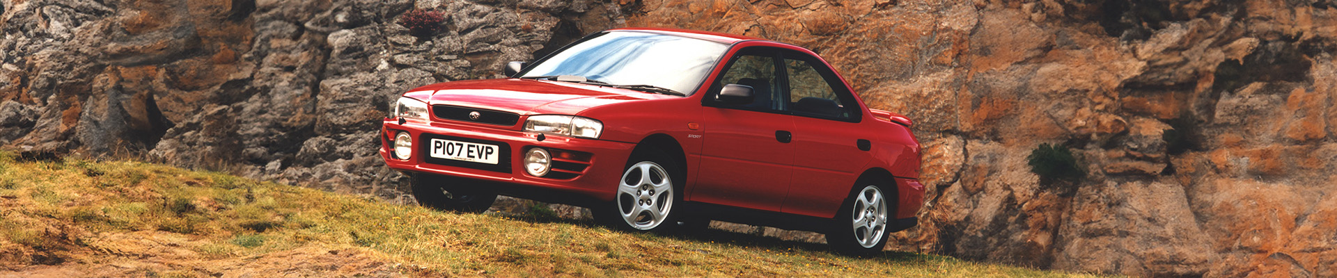 Red Subaru Impreza parked in a field